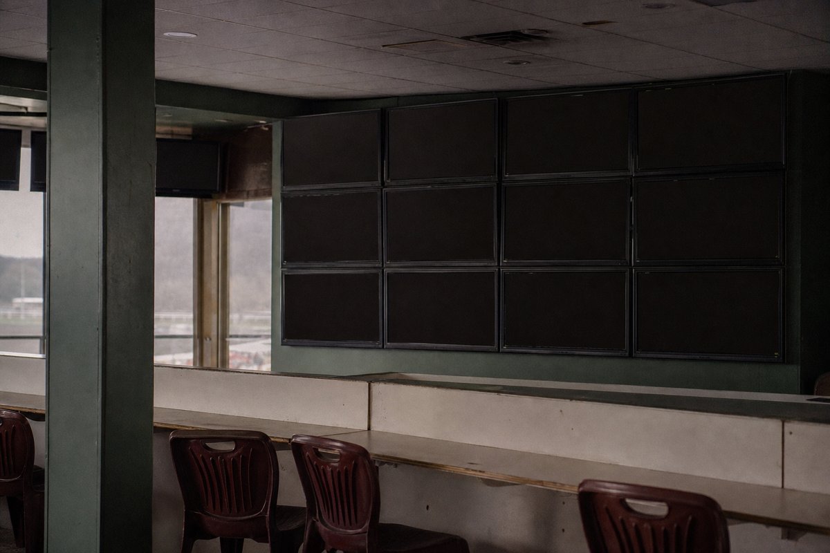 A betting floor with a grid of screens mounted above empty counters